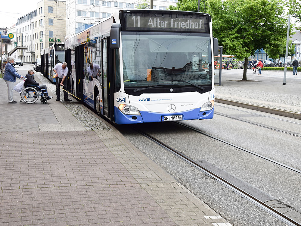 Ein Bus steht mit eingeschaltetem Warnblinklicht an einer Haltestelle am Straßenrand. Nachfolgende Autofahrer wissen in dieser Situation oft nicht, wie sie reagieren sollen – warten oder vorbeifahren?